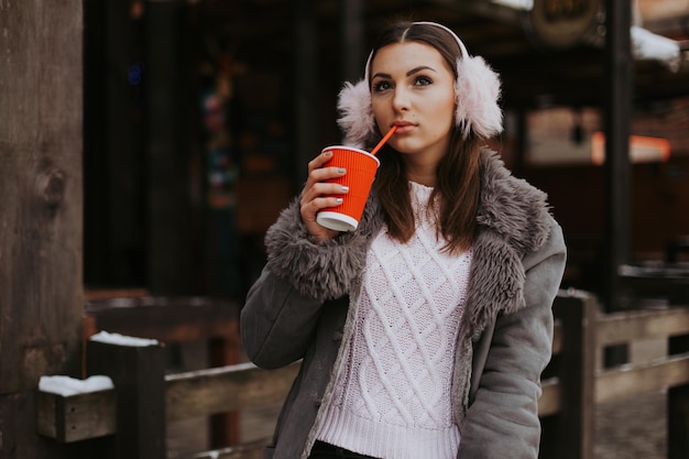 Senhora de inverno sorridente com a xícara de chá no fundo da neve