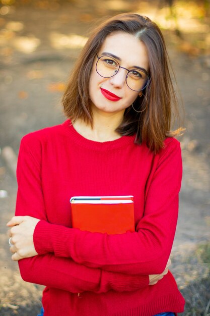 Senhora de suéter vermelho lê na natureza. menina e livro