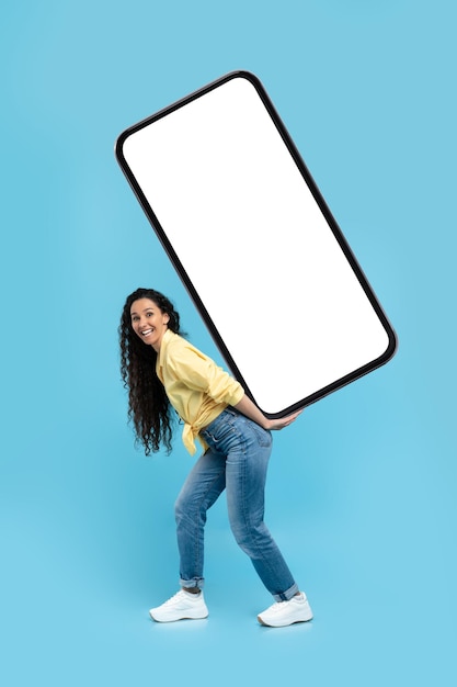 Senhora do Oriente Médio carregando enorme tela de celular sobre fundo azul