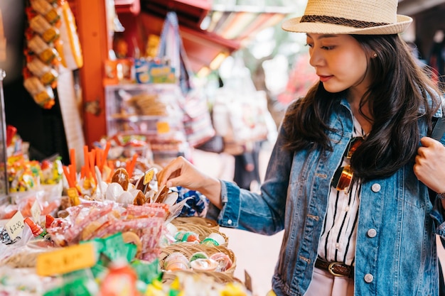 senhora elegante escolhendo doces no vendedor de doces no mercado tradicional. viajante olhando as especialidades em fornecedores mexicanos ao ar livre. viajar no estilo de vida da América.