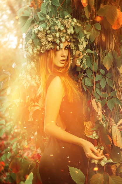 Senhora encantadora com uma coroa de lúpulo na floresta mágica ao ar livre