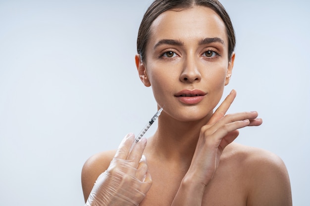 Foto senhora encantadora está pronta para procedimentos de beleza contra um fundo claro