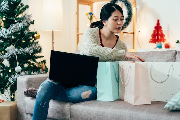 senhora está verificando presentes enquanto discute sobre a festa de Natal da família no pc. mulher está comprando presentes de natal na internet e acompanhando os presentes que ela já comprou.