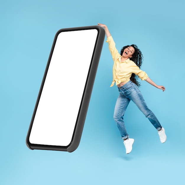 Senhora excitada mostrando a tela branca vazia do smartphone e pulando