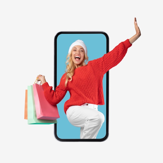 Senhora excitada olhando para a tela do celular com sacolas de compras