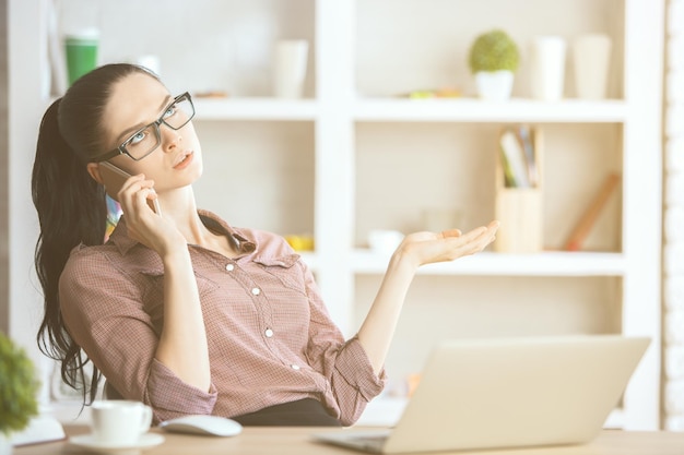 Senhora falando ao telefone no local de trabalho