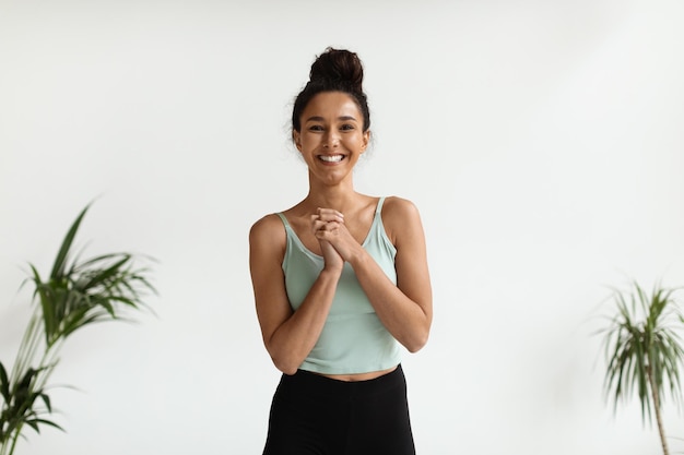 Foto senhora feliz em roupas esportivas em pé com as mãos entrelaçadas e sorrindo para a câmera