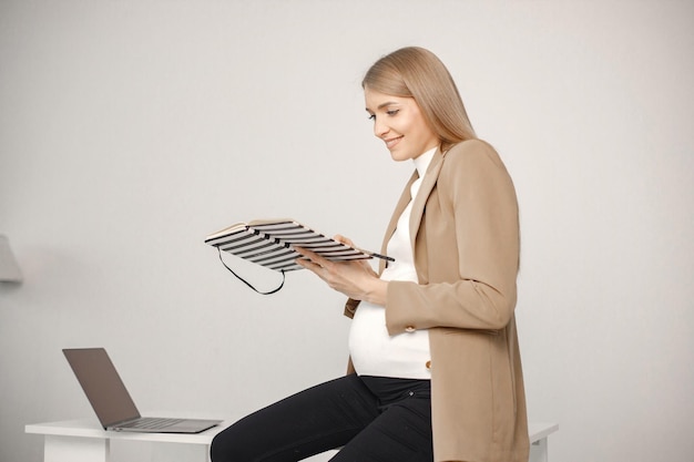 Senhora grávida com notebook sentado na mesa no escritório moderno