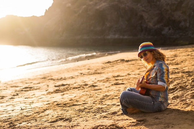 Senhora hippie de boa liberdade em férias cantando uma música em atividade de lazer ao ar livre na praia durante o pôr do sol