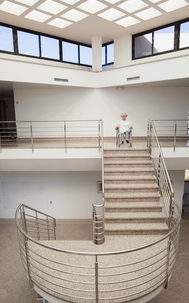 Senhora idosa em cadeira de rodas no topo da escada