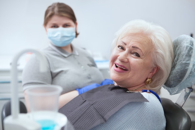 Foto senhora idosa feliz sorrindo para a câmera, após exame dentário na clínica