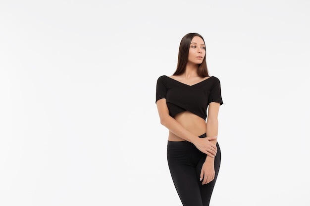 Senhora magra atraente em top preto e leggings abraçando o corpo e olhando para a câmera