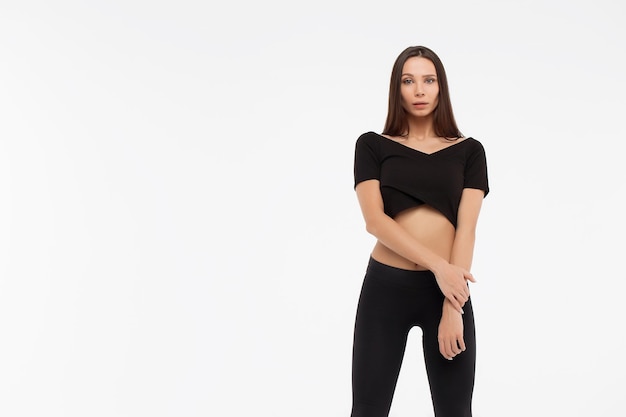 Senhora magra atraente em top preto e leggings abraçando o corpo e olhando para a câmera