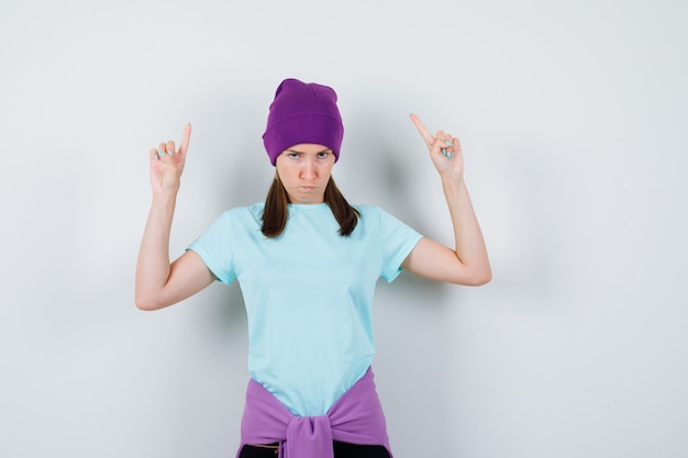 Senhora maravilhosa de blusa, gorro apontando para cima e parecendo confiante, vista frontal.