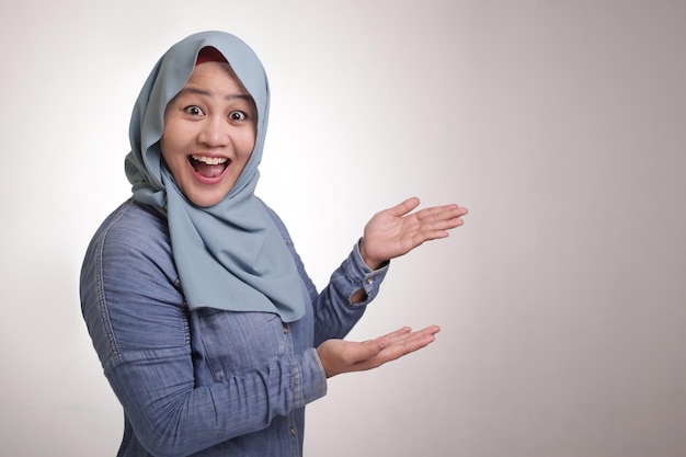 Senhora muçulmana apresentando algo ao seu lado com espaço para texto