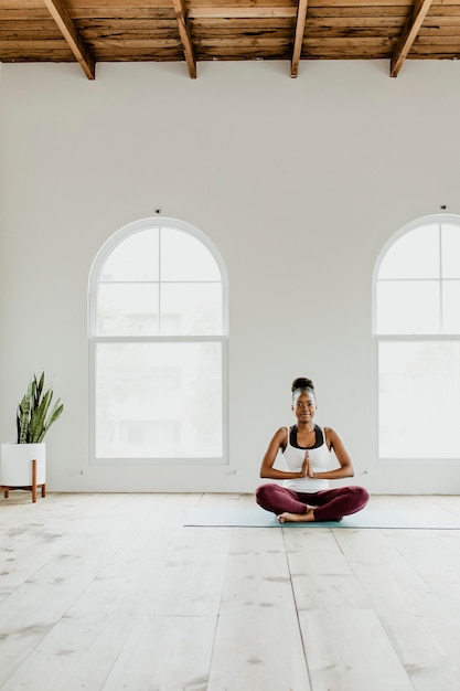 Senhora negra fazendo uma pose de ioga Sukhasana