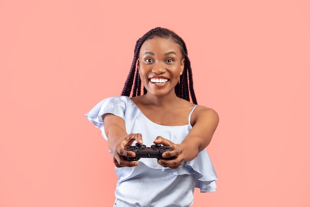 Senhora negra milenar animada com joystick jogando videogame no fundo do estúdio rosa