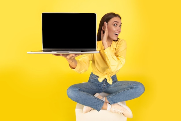 Foto senhora ouvindo laptop com tela em branco sobre fundo amarelo