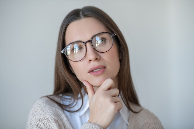 Senhora pensativa. Foto na cabeça de uma mulher de cabelo comprido usando óculos parecendo pensativa