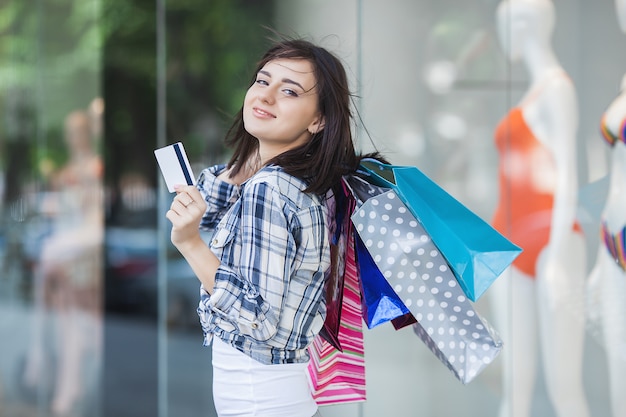 Senhora segurando sacolas de compras e cartão de crédito