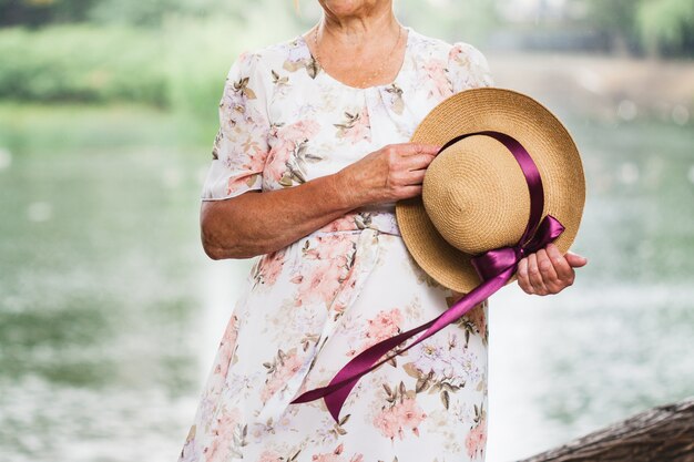 Senhora, segurando um chapéu com uma fita na mão, passear no parque em um dia ensolarado de verão, data, amor