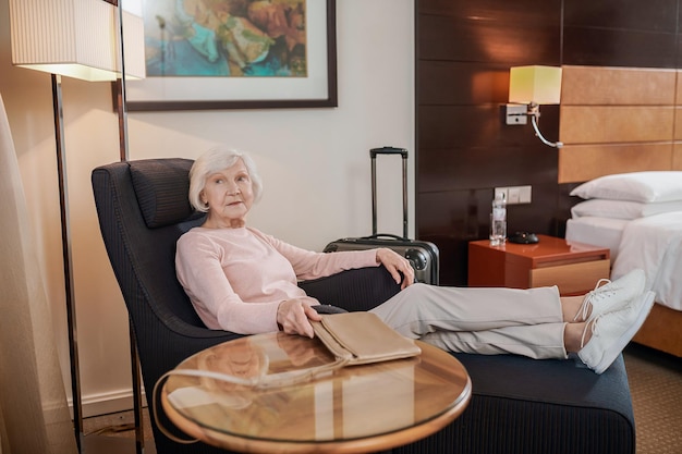 Senhora sênior elegante de cabelos curtos em um quarto de hotel