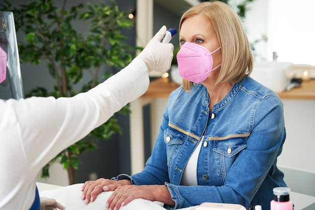 Senhora sênior usando máscara em salão de manicure