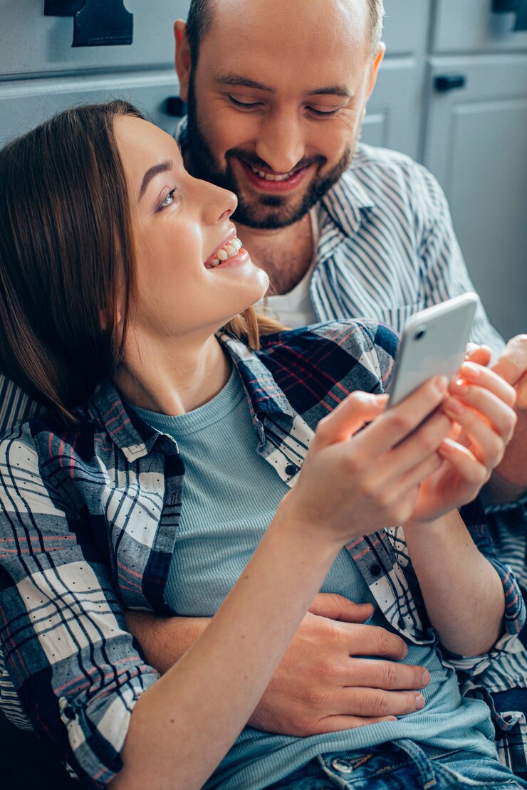 Senhora sorridente com smartphone na mão olhando para o namorado