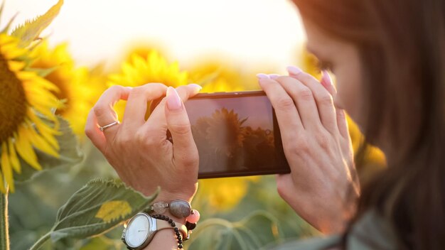 Senhora turista tira foto de girassol brilhante na câmera do telefone