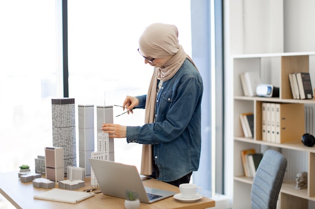 Senhora usando bússola e laptop no escritório de arquitetura