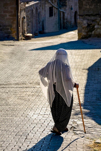 Senhora velha vestindo as roupas e o véu islâmico caminhando pelas ruas de Goreme na Capadocia, Turquia