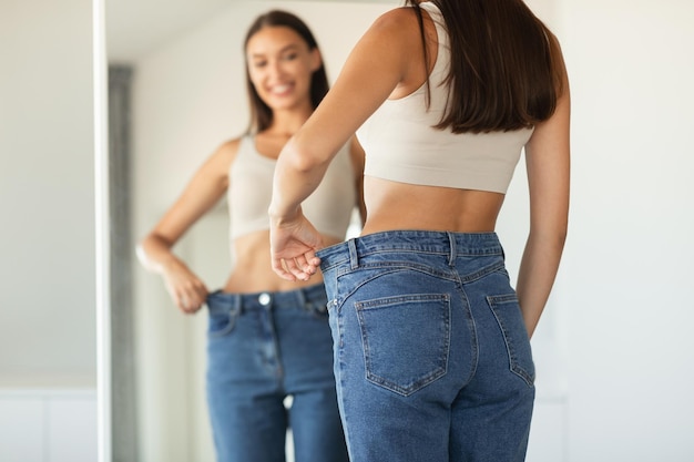 Foto senhora vestindo jeans oversized comparando o tamanho depois de emagrecer em casa