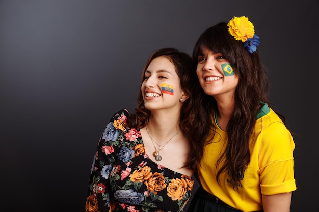 Senhoras brasileiras e equatorianas com arte corporal em seus rostos olhando para frente surpresas Pintura colorida Foco seletivo