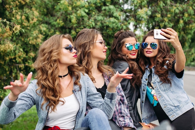 Senhoras da moda com penteado tomando selfie ao ar livre.