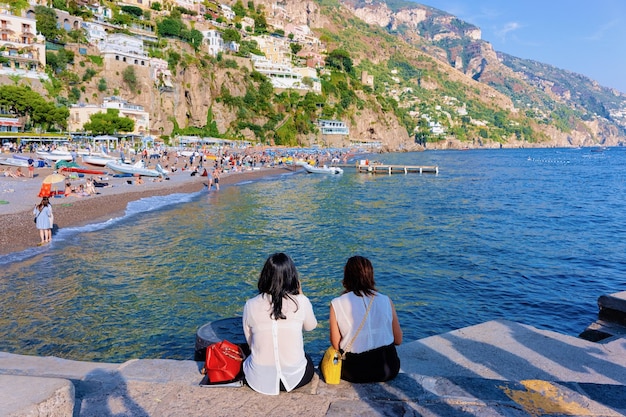 Senhoras sentadas na praia na cidade de Positano, na Costa Amalfitana e no Mar Tirreno, na Itália, no verão. Mulheres e bela vista do Mediterrâneo perto de Sorrento.