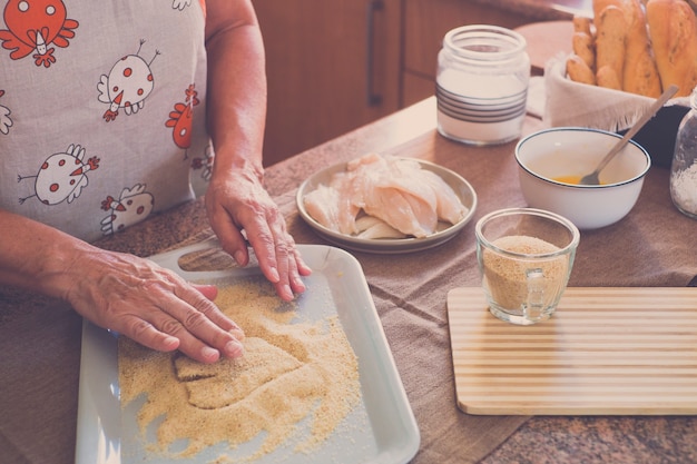 Senior allein zu Hause kochen Fisch in der Küche - sehr konzentriert drinnen - reife und kaukasische Frau der 60er Jahre - Frau im Ruhestand