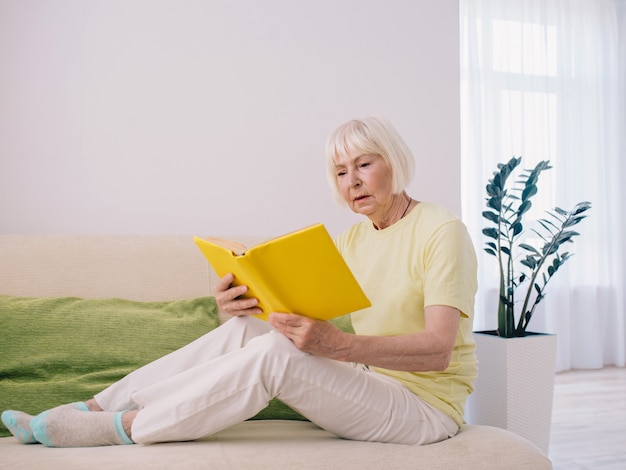 Senior anciana con canas leyendo un libro en casa Pensión de educación lectura anti edad