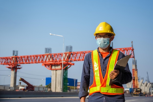 Senior Asian Engineer Construction sind Arbeiter, die mit einem Sicherheitskontrollhelm vor Ort arbeiten