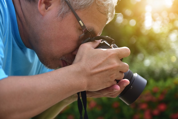 Senior con cámara de 45-55 años y toma una foto en un parque público