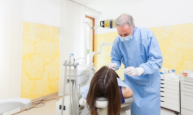 Senior dentista curar a un paciente femenino