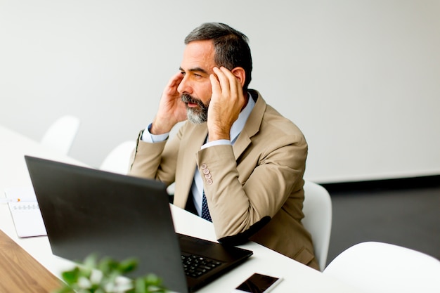 Senior Director, der am Schreibtisch sitzt und an Laptops im Büro arbeitet