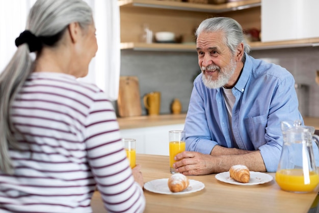 Senior Ehepaar im Chat beim gemeinsamen Frühstück in der Küche