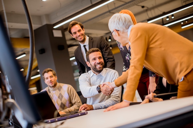 Senior empresaria trabajando junto con jóvenes empresarios en la oficina moderna