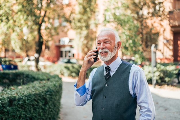 Senior exitosa hablando por teléfono al aire libre.