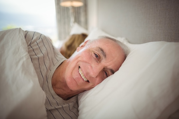 Sênior feliz deitado na cama