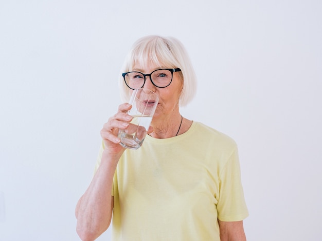 Senior Frau mit Glas Wasser und Trinkwasser Gesunder Lebensstil Sport Anti-Age-Konzept