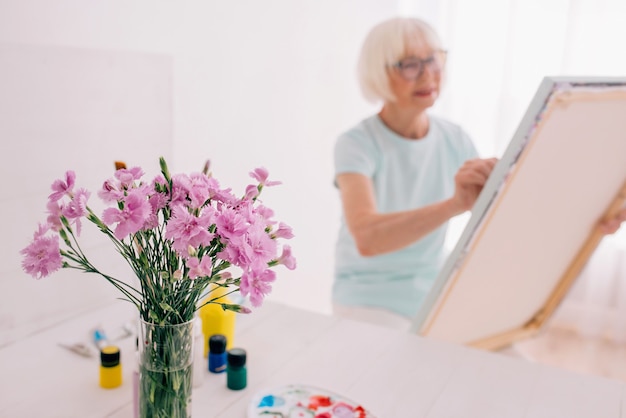 Senior fröhliche Frau mit Brille mit grauen Haaren Malerei Stillleben Kreativität Kunst Hobby