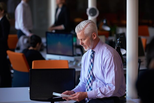 Senior Geschäftsmann mit seinem Team im Büro. Gruppe von Geschäftsleuten