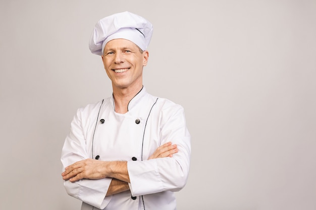 Senior guapo chef cocinero aislado en la pared gris.