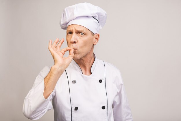 Senior guapo chef cocinero aislado en la pared gris.